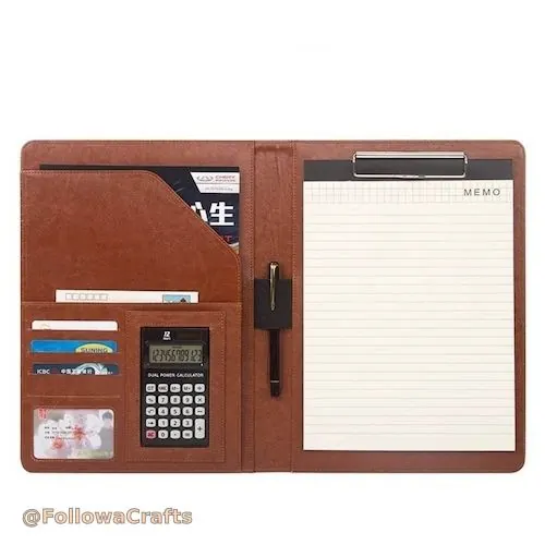 Schwaarz Lieder Padfolio oppe mat Sëlwer Rechner an Notizblock